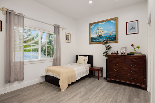 A cozy and well-lit bedroom featuring minimalist design with natural light filtering through the window.