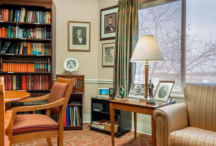 A cozy office space with a bookshelf, desk, and comfortable seating.