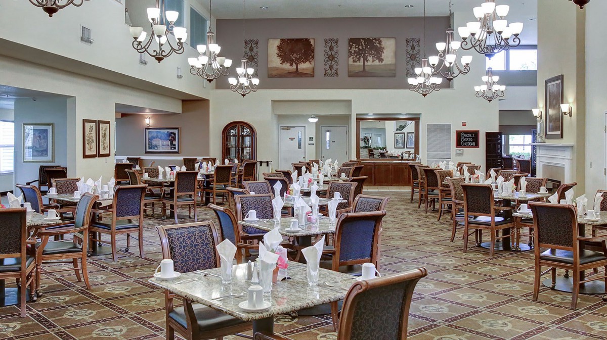 Elegant dining room interior with neatly arranged tables and chandeliers.