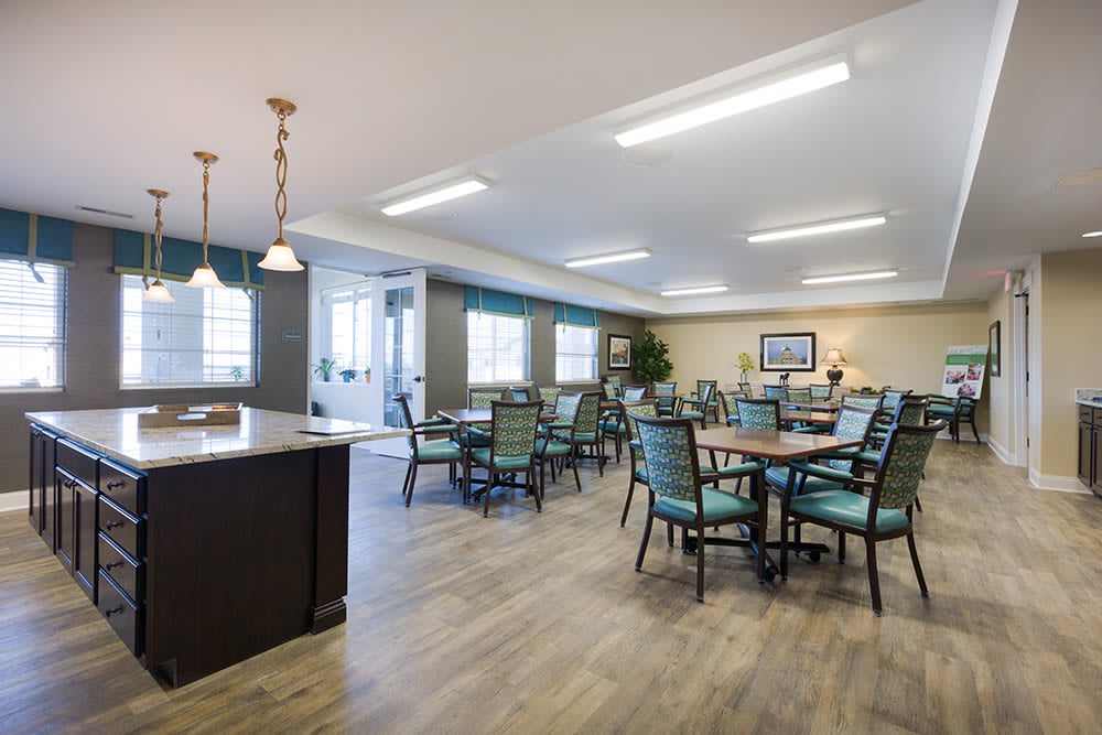 A spacious and modern dining area featuring several tables and chairs, with elegant lighting fixtures.
