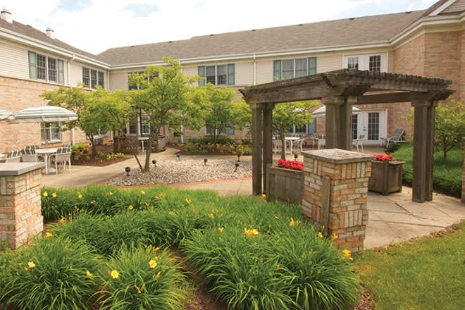 A well-maintained courtyard garden with lush greenery and a brick structure.
