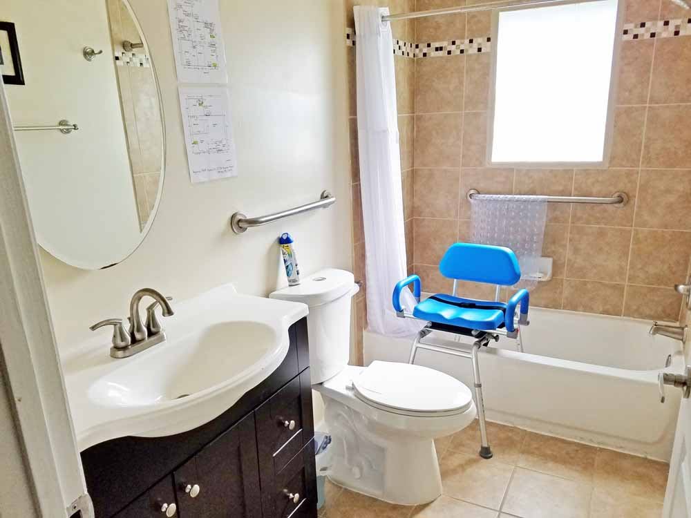 A clean and accessible bathroom with a blue shower chair in the bathtub.