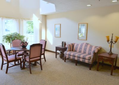 A cozy, well-lit living room with a striped sofa, dining table, and chairs.