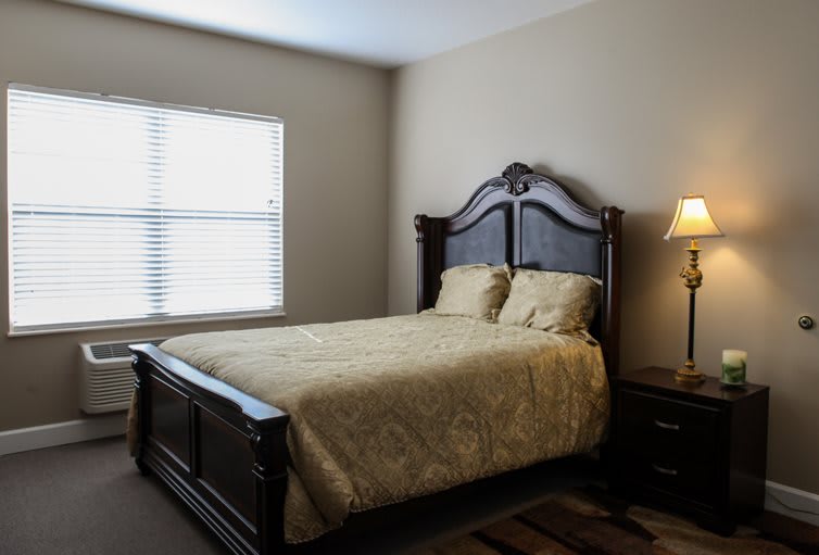 A cozy bedroom with a large bed and bedside lamp.