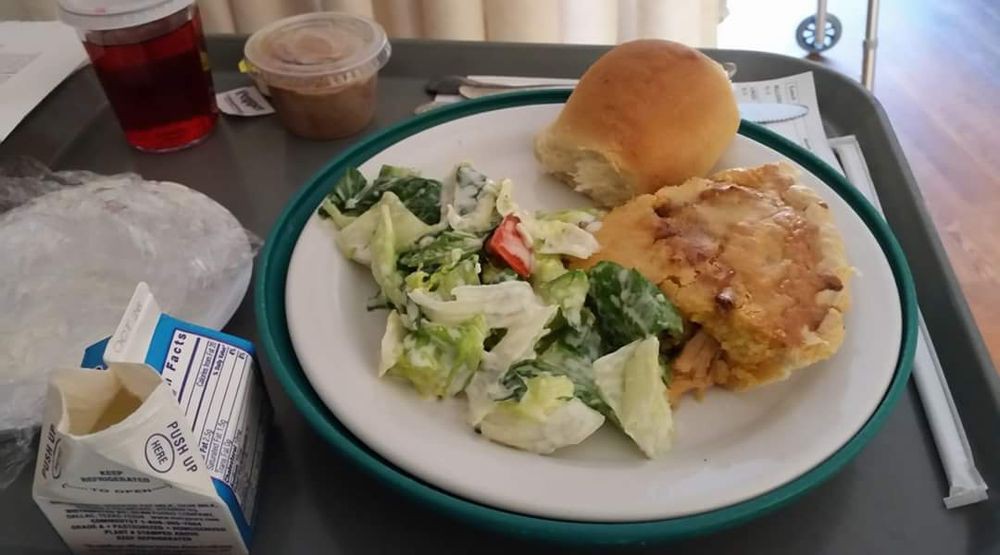 A meal consisting of a fresh salad, a bread roll, and an omelet on a plate.