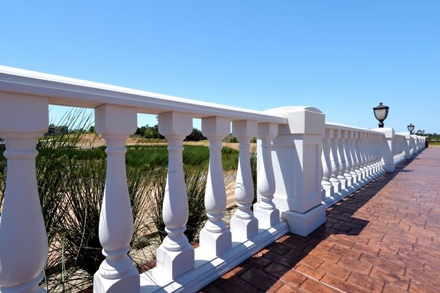 A white balustrade with a bright sunny landscape in the background.