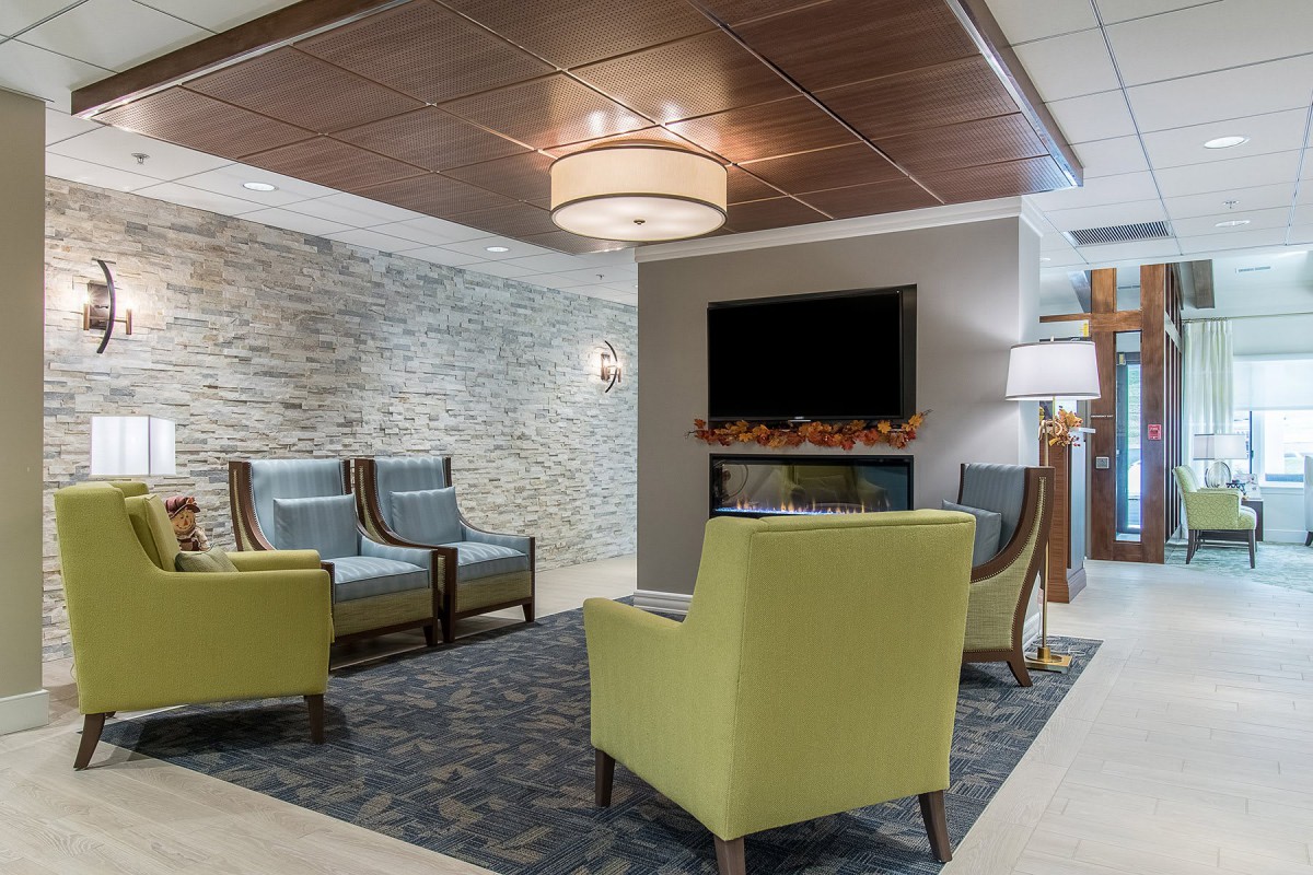 A modern lobby area with comfortable seating, a stone accent wall, and a cozy fireplace below a television.