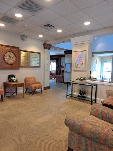 A welcoming waiting area featuring comfortable chairs and a stylish table, designed for relaxation in a well-lit lobby.