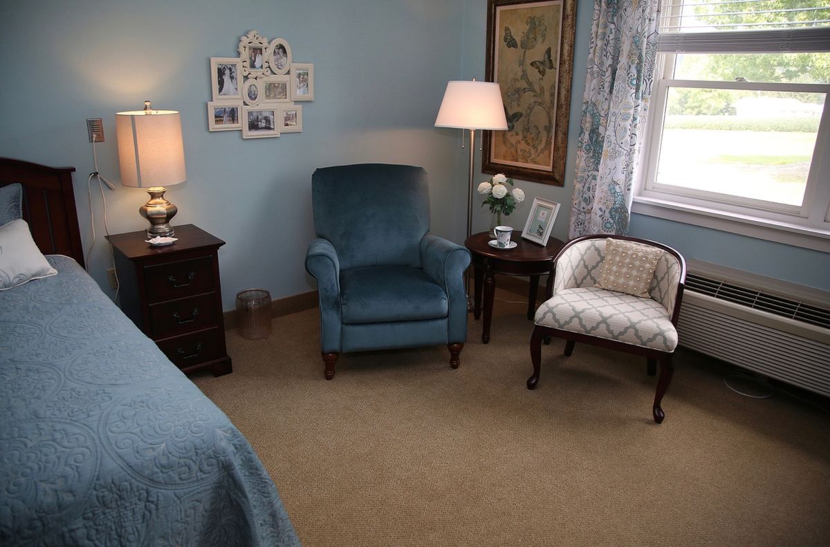 A cozy bedroom corner with a blue armchair and decorative elements.