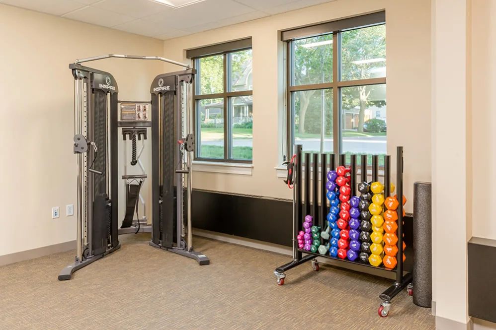 A compact gym space equipped with various dumbbells and an exercise machine.