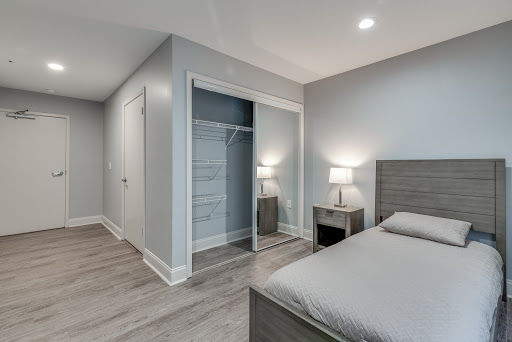 A modern minimalist bedroom featuring gray walls, laminate flooring, and stylish furnishings.
