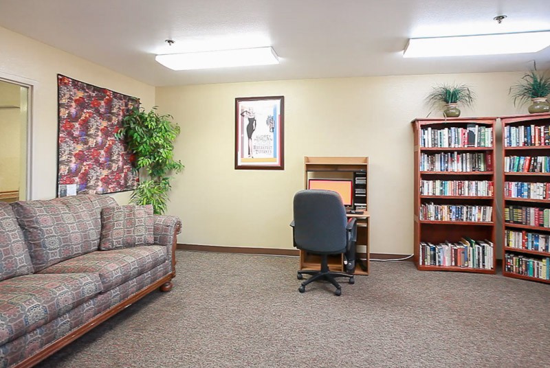 A neatly arranged office space featuring a desk with a computer, a bookshelf filled with books, and a comfortable sofa.