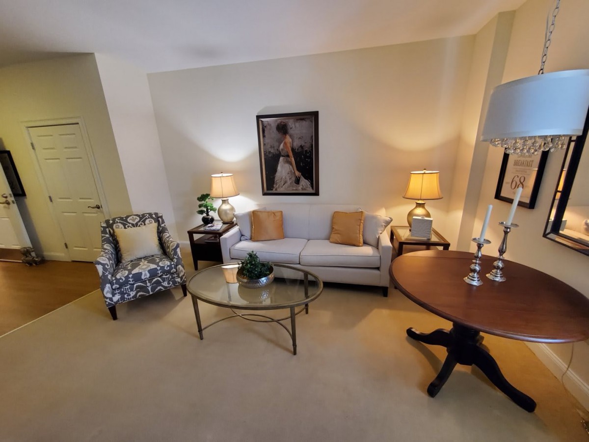 A cozy living room featuring a sofa, armchair, coffee table, and warm lighting.