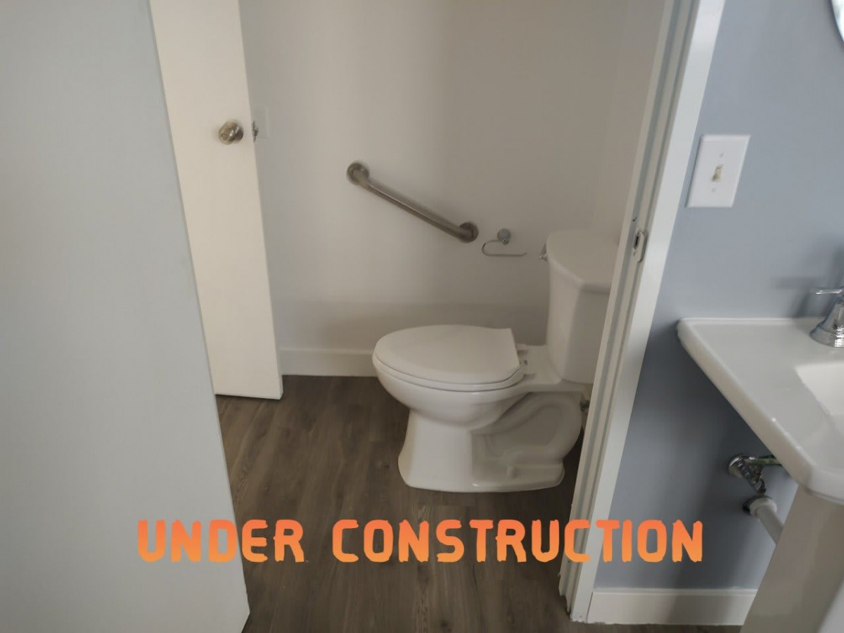 A bathroom under construction with a toilet and grab bar installed.