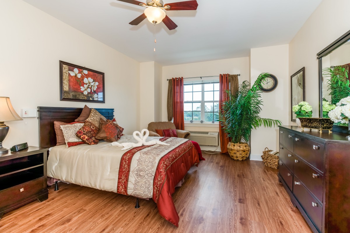 A well-decorated bedroom with a comfortable bed, wooden flooring, and elegant furnishings.