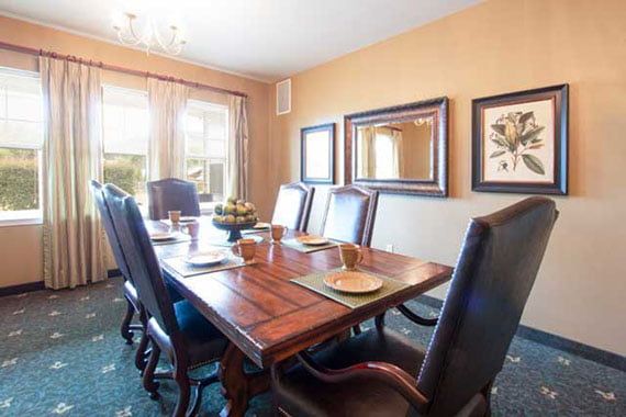 A well-decorated dining room with a wooden table, upholstered chairs, and decorative mirrors on the wall.