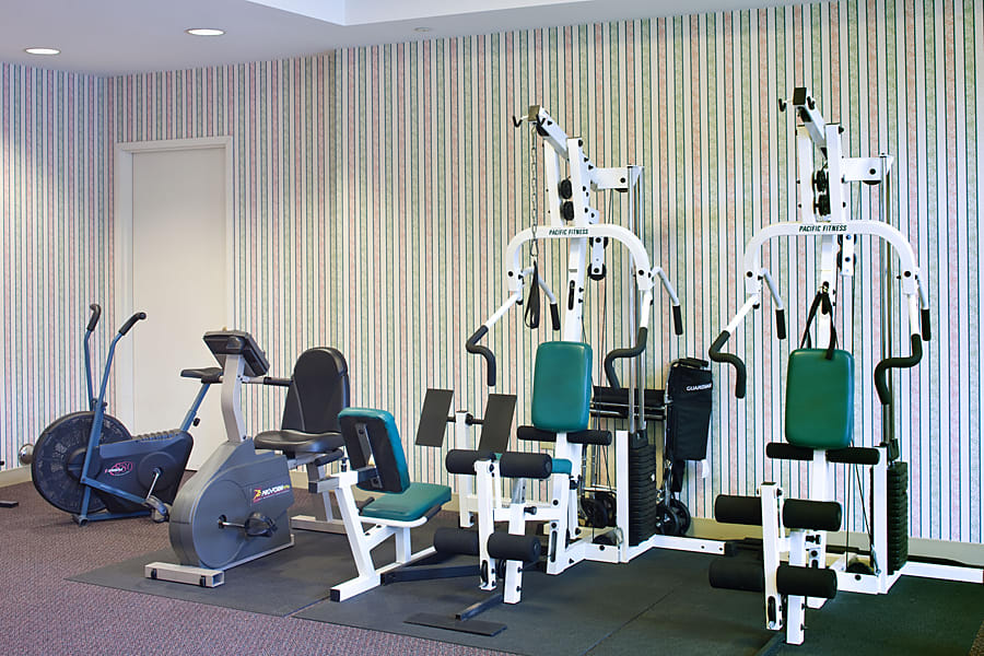 A gym room featuring various exercise machines and fitness equipment.