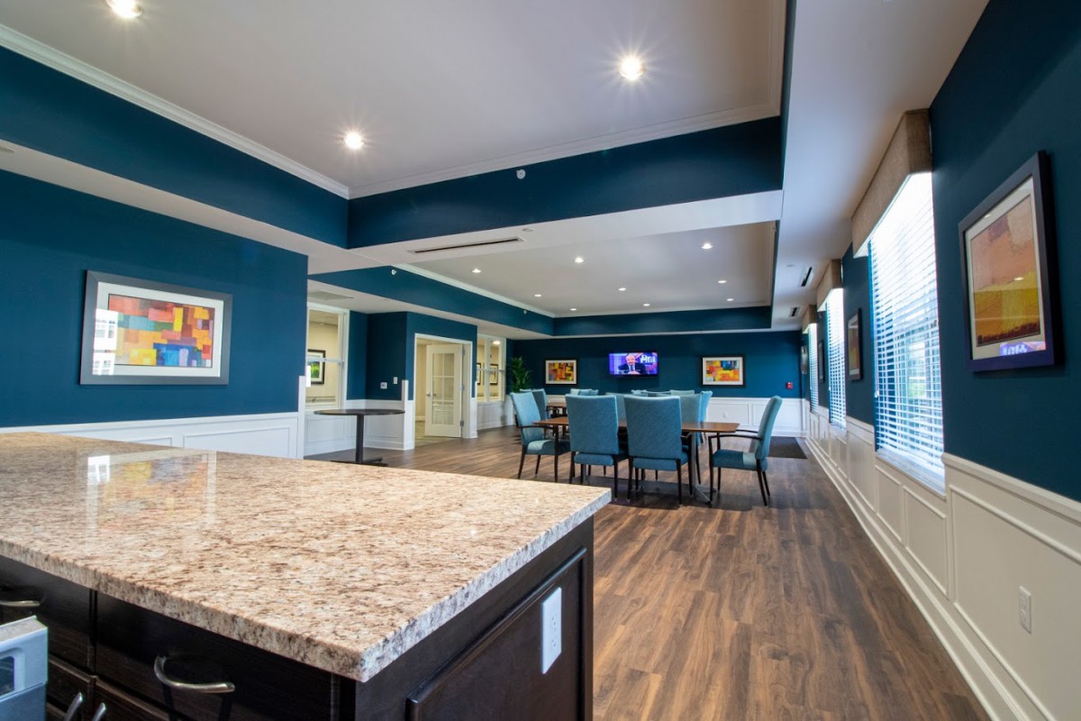 A modern conference or dining room with blue walls, wooden floors, and a large table surrounded by chairs.