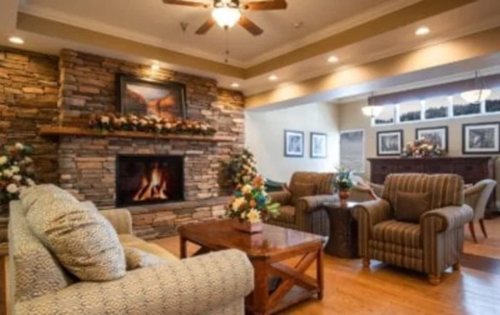 A cozy living room with a stone fireplace and comfortable seating.