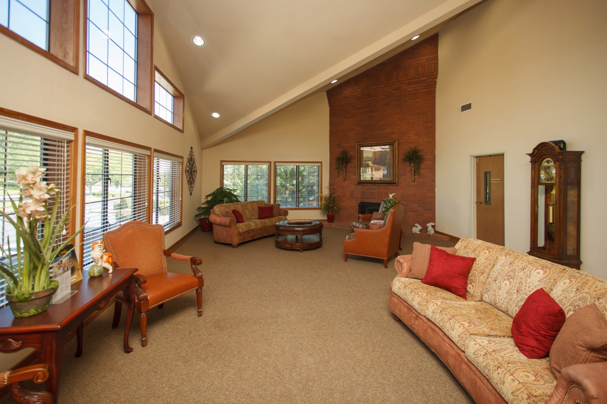 A spacious living room with high ceilings, featuring comfortable sofas and a fireplace.