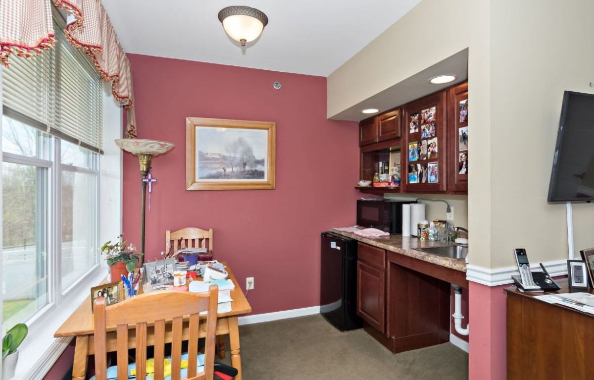 A cozy kitchenette with a dining area, featuring warm-colored walls, wooden cabinets, and a small dining table set.