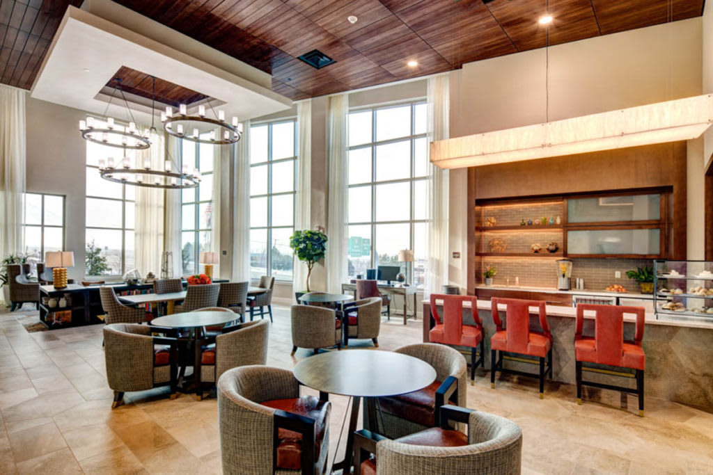 A modern restaurant interior featuring a spacious dining area with elegant lighting fixtures and a cozy bar section.