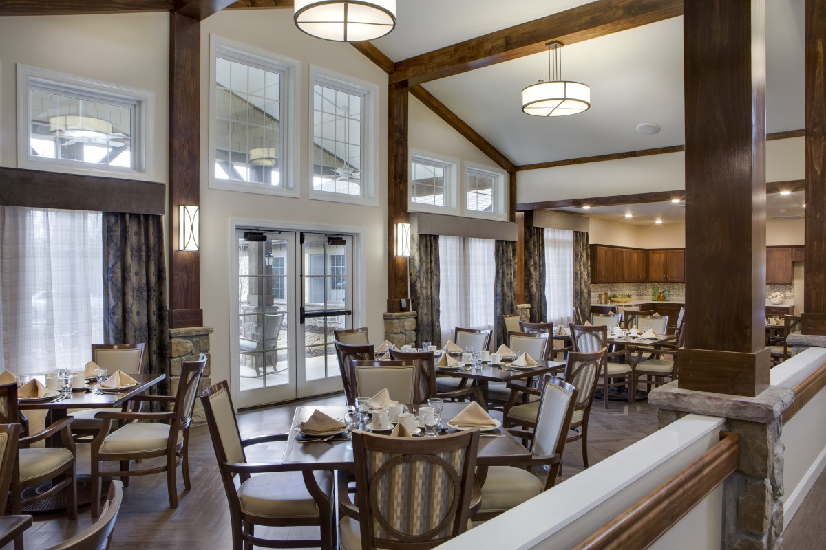 A spacious and elegant dining room with neatly arranged tables and chairs, featuring large windows and modern lighting fixtures.