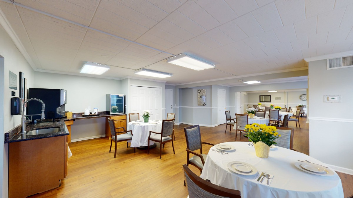 A cozy dining area with neatly arranged tables and chairs, decorated with flowers and soft lighting.