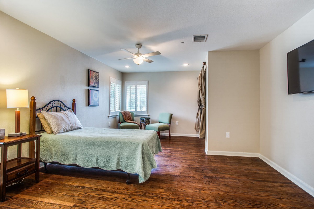 Spacious bedroom with wooden flooring and simple furnishings.