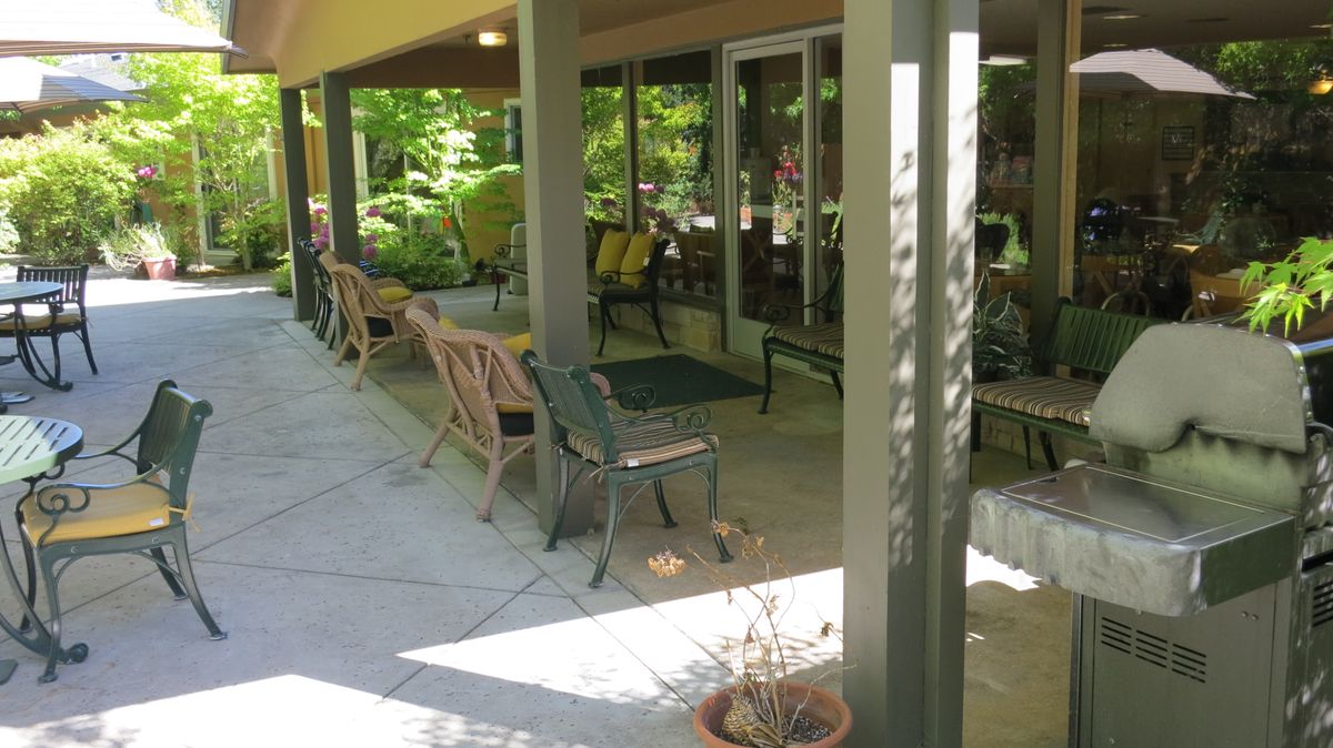 A peaceful patio area with seating and potted plants, bathed in sunlight.