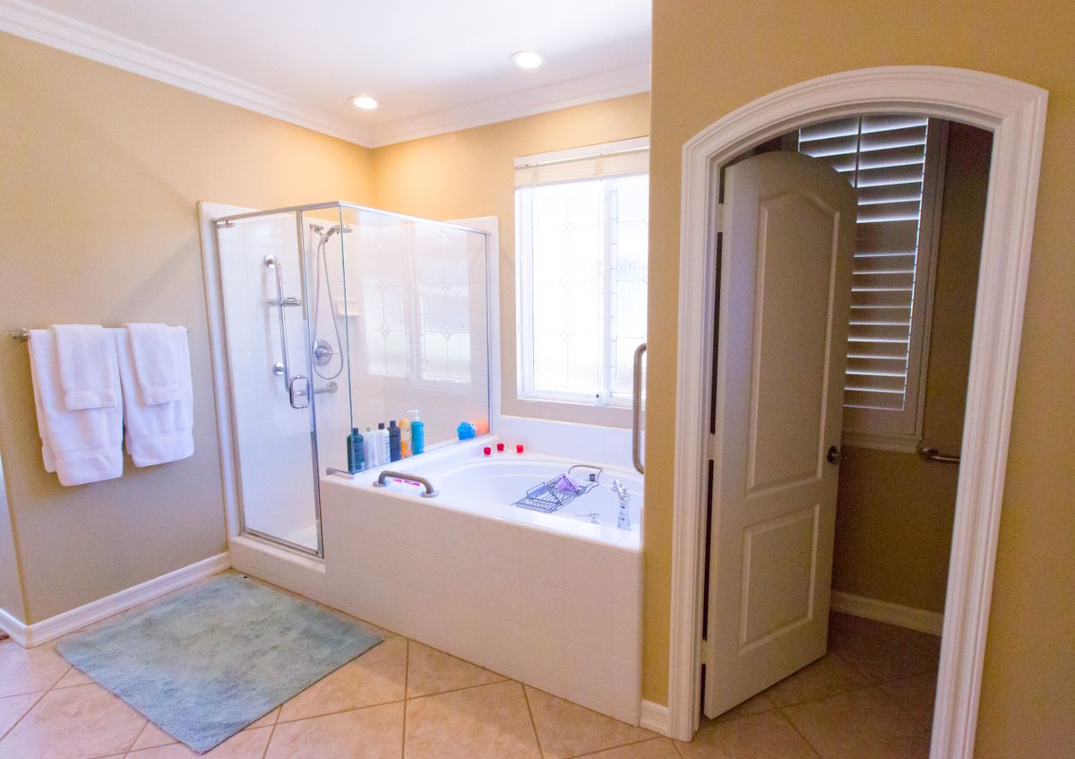 A modern bathroom featuring a bathtub and a shower area with natural light streaming through the window.