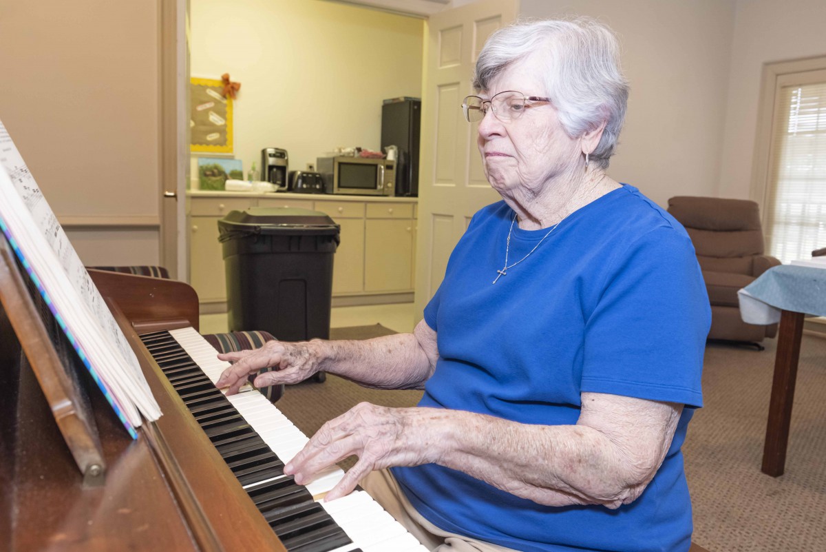 An elderly woman playing the piano indoors.