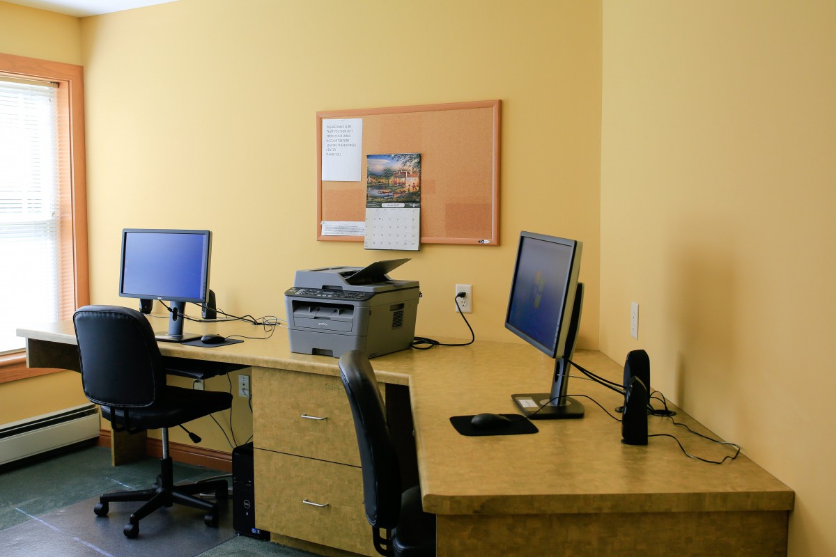 A modern office workstation featuring desks with computers, chairs, and a printer.