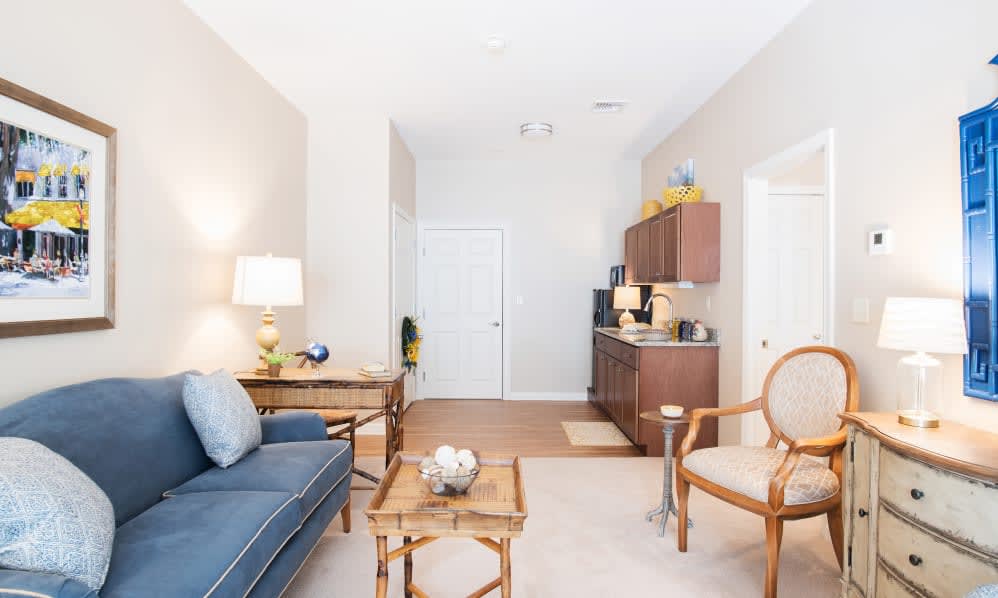 A cozy living room with a blue sofa, wooden coffee table, and adjacent kitchenette.