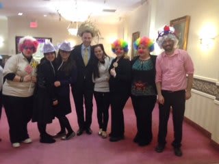 A group of people wearing colorful clown wigs and hats indoors.