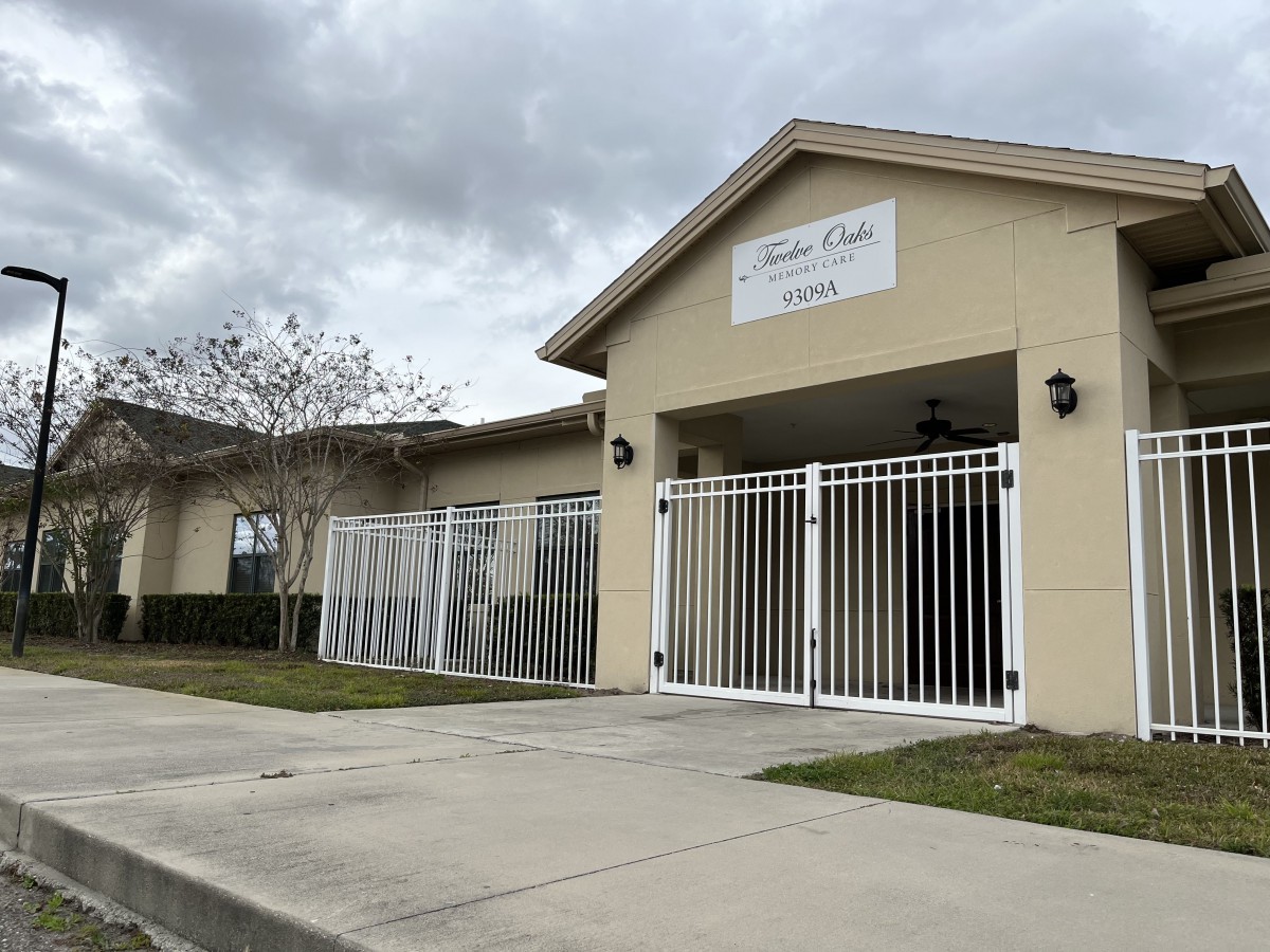 A small building with a gated entrance under a cloudy sky.