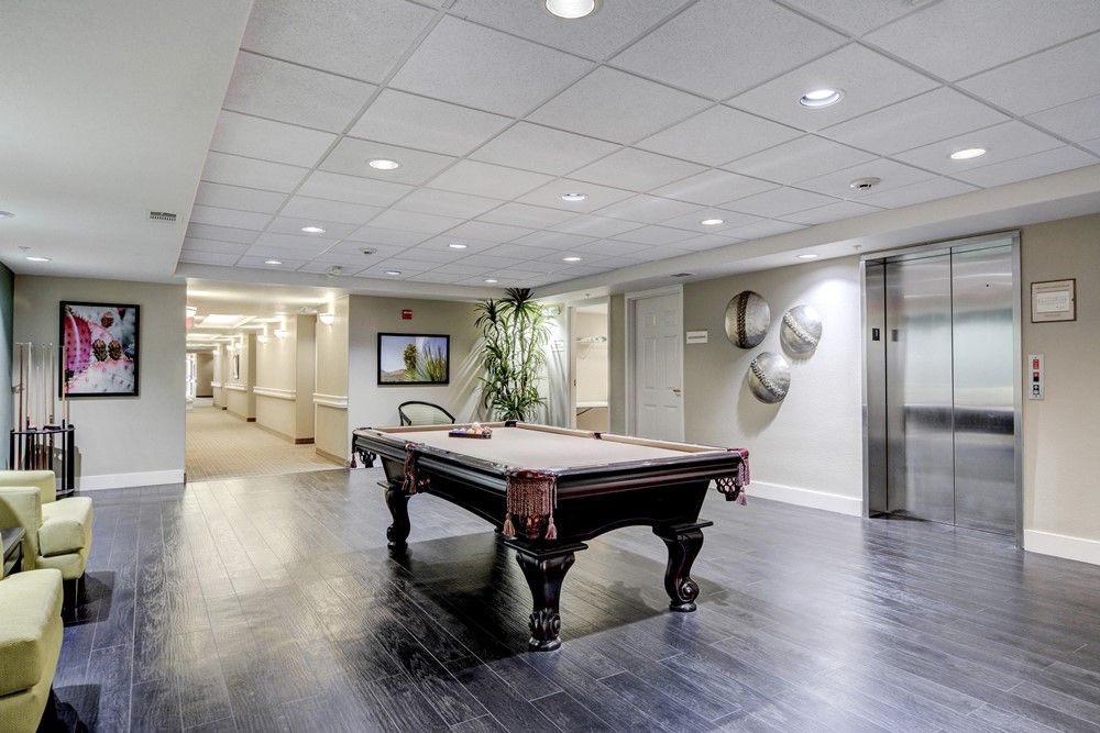 A modern lounge area featuring a billiards table, with an adjacent hallway and elevator.