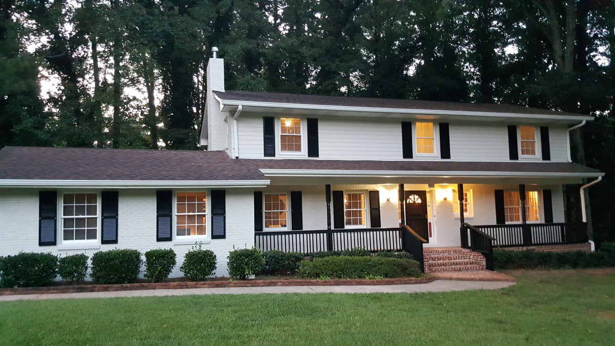 A cozy two-story suburban house surrounded by trees.