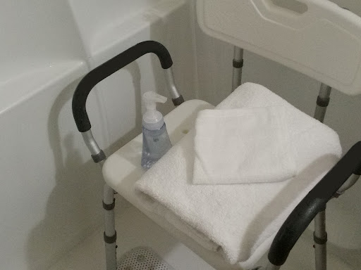 A shower chair equipped with towels and a bottle of liquid soap for personal care.