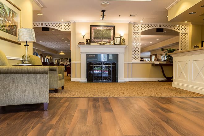 A spacious and elegantly decorated living area featuring a fireplace, comfortable seating, and hardwood flooring.