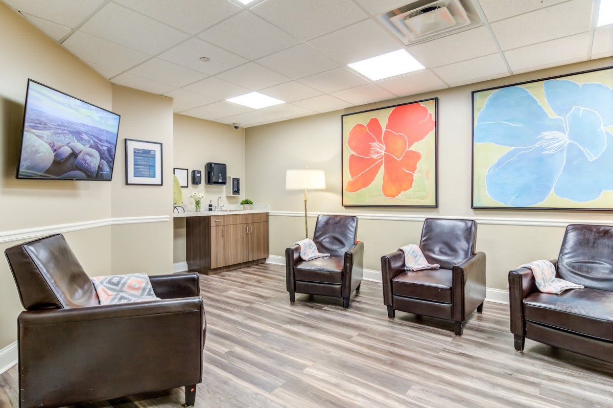A modern waiting room featuring comfortable chairs and vibrant artwork on the walls.