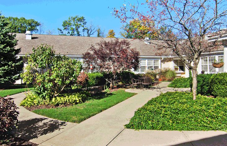 A quaint house with a well-maintained garden and paved pathways.
