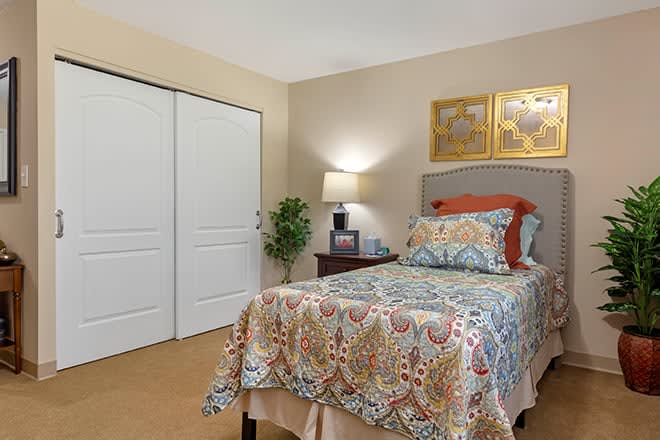 A cozy bedroom with a single bed, patterned bedding, and warm lighting.