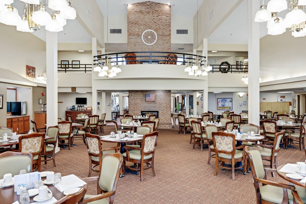 Spacious dining area with elegantly set tables and chairs, featuring a high ceiling and chandeliers.