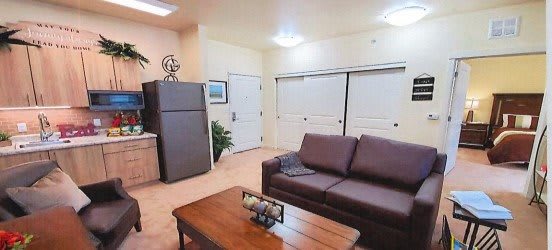 A cozy living room with a brown sofa, coffee table, and a fridge in the corner.