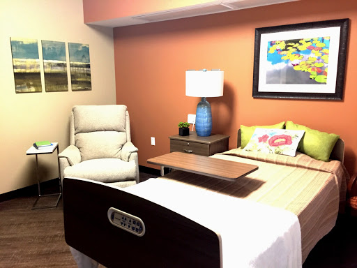 A well-decorated hospital room featuring a patient bed, a comfortable chair, and colorful artwork.