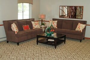 A cozy living room with matching sofas, a patterned carpet, and a central coffee table.