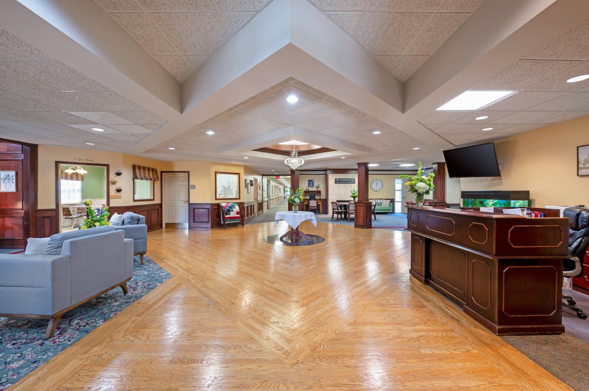 A spacious and modern lobby with wooden flooring, comfortable seating, and decorative plants.