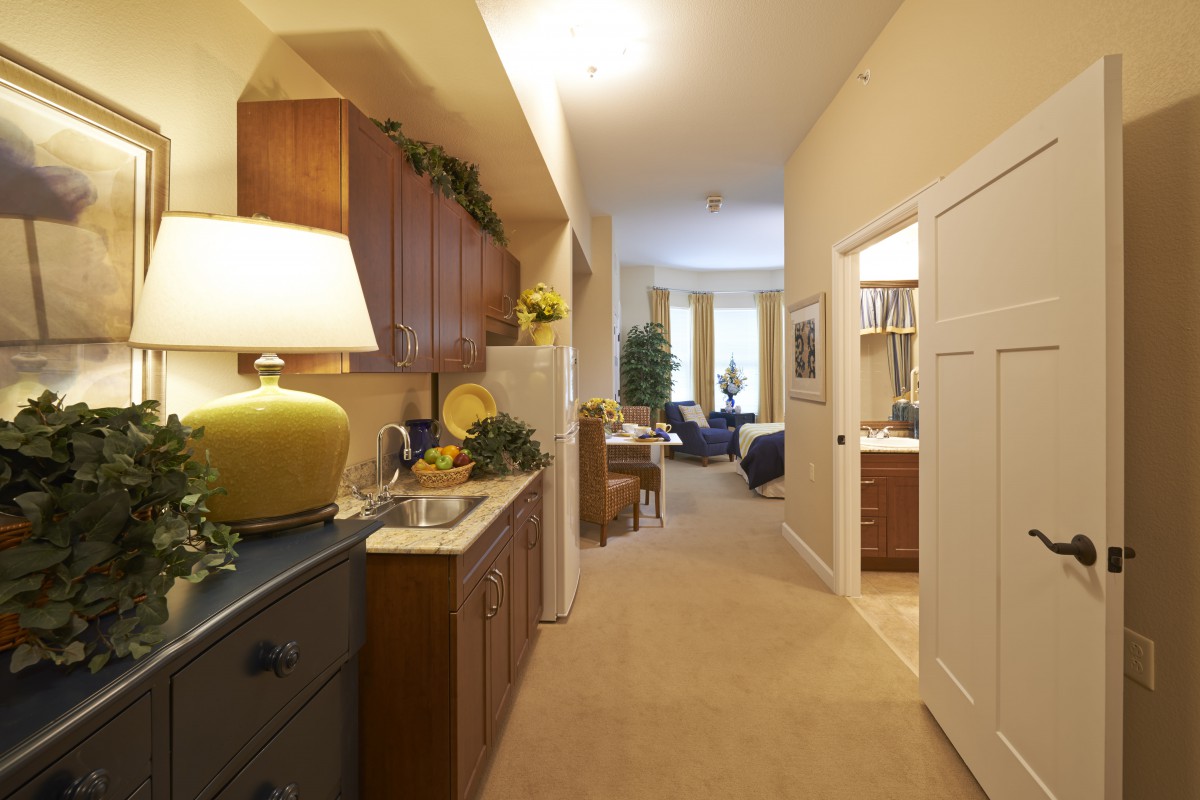A cozy apartment interior featuring a compact kitchen and a hallway leading to the living room.