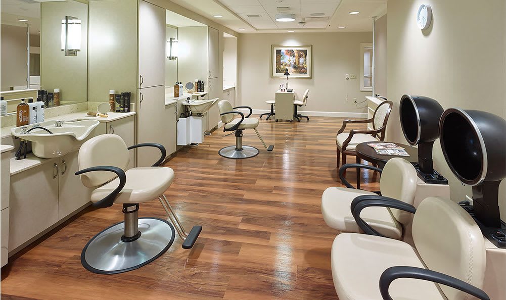 A modern hair salon interior with styling chairs, mirrors, and a wooden floor.